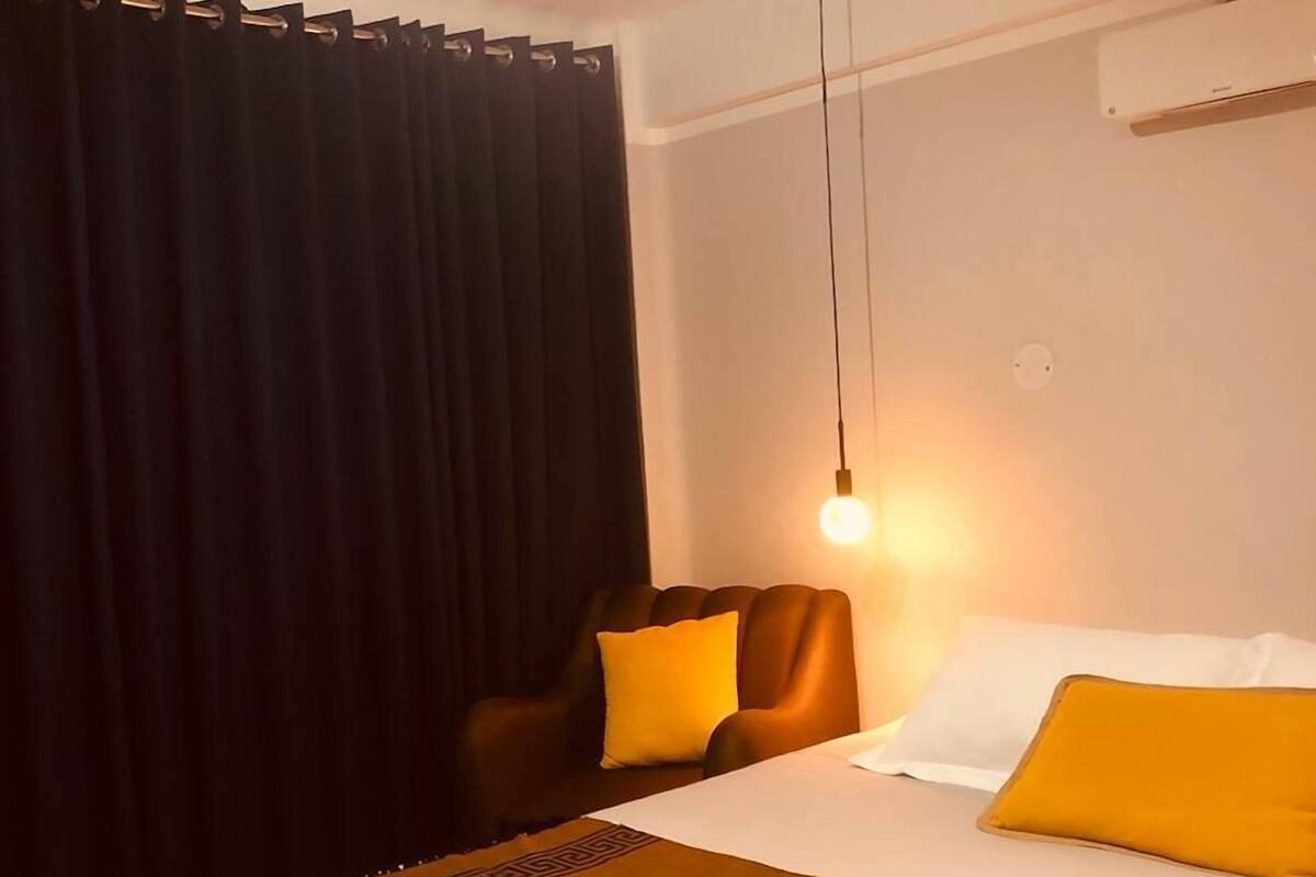 A hotel room with a bed, a chair, a lamp, and a window with curtains.