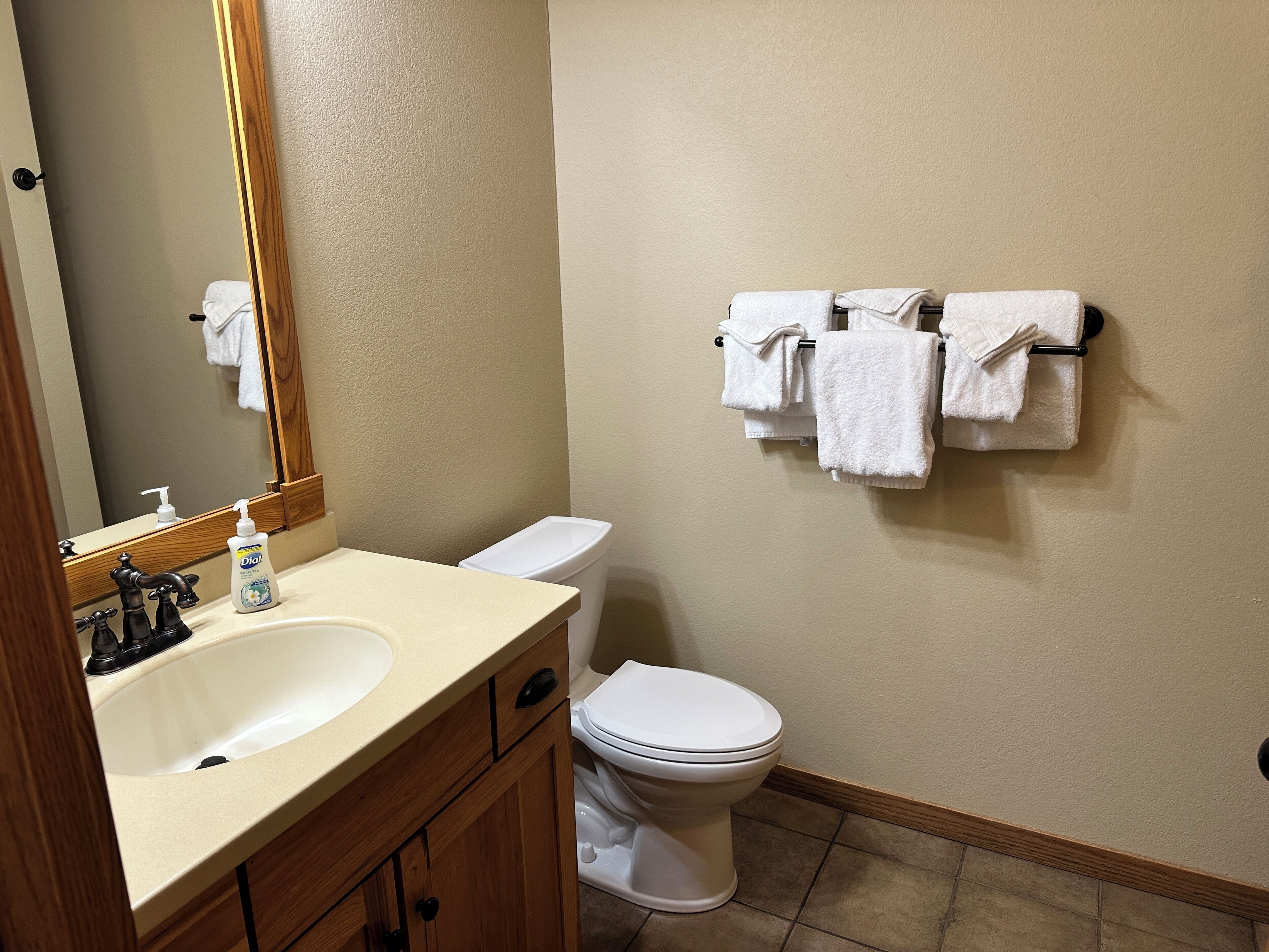 A bathroom with a sink, mirror, toilet, and towel rack.