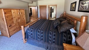 A bedroom with a bed, wooden wardrobe, ceiling fan, and framed pictures on the wall. - Spirit of the Northwoods (eagle river)