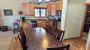A spacious kitchen with wooden cabinets, a large dining table, and a built-in microwave. - Spirit of the Northwoods (eagle river)