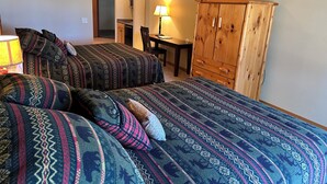 A bedroom with two beds, a wooden wardrobe, a desk, and a lamp. - Studio 112 By Eagle Waters Resort (eagle river)