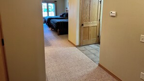 A hallway leading to a bedroom with two beds, a wooden door, and a ceiling fan. - Studio 112 By Eagle Waters Resort (eagle river)