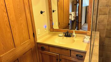 Une salle de bain avec des meubles de rangement en bois, un lavabo, un miroir et un porte-serviettes.
