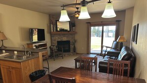 Una cocina con salpicadero de piedra, chimenea y comedor con mobiliario de madera.