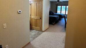A hallway leading to a bedroom with two beds, a ceiling fan, and a window with a view. - Studio 113 By Eagle Waters Resort (eagle river)