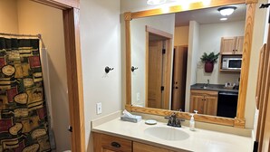 A bathroom with a wooden vanity, a sink, a mirror, and a toilet. - Studio 113 By Eagle Waters Resort (eagle river)
