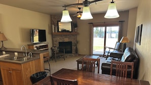 A kitchen with a stone backsplash, a fireplace, and a dining area with wooden furniture. - CONDO 103 by Eagle Waters Resort (eagle river)