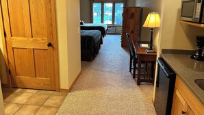 A hallway leading to a bedroom with two beds, a ceiling fan, and a window with curtains. - CONDO 105 by Eagle Waters Resort (eagle river)