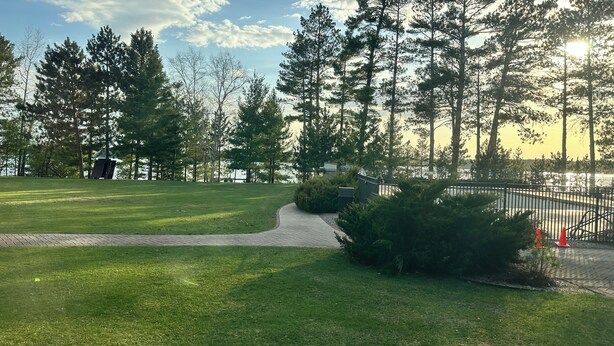 A park with a paved walkway, grassy areas, and tall trees. - CONDO 105 by Eagle Waters Resort (eagle river)