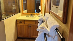 Ein Badezimmer mit einem Holzkosmetikschrank, einem großen Spiegel und einem Handtuchhalter.