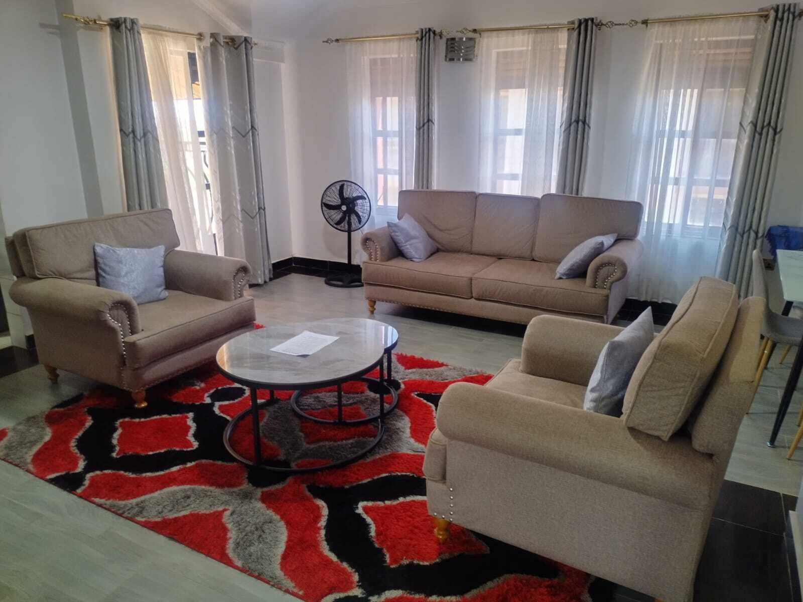 Una sala de estar con dos sofás, una mesa de centro y un ventilador.