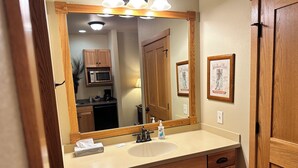 A bathroom with a wooden vanity, a large mirror, and a sink. - Studio 115 By Eagle Waters Resort (eagle river)