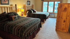 A bedroom with two beds, a ceiling fan, a window with curtains, and a wooden wardrobe. - Studio 115 By Eagle Waters Resort (eagle river)