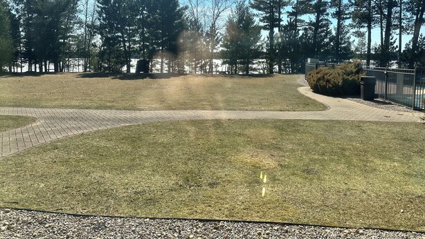 A park with a paved walkway, grassy areas, and tall trees. - CONDO 106 by Eagle Waters Resort (eagle river)
