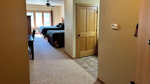 A hallway leading to a bedroom with two beds, a ceiling fan, and a door. - CONDO 106 by Eagle Waters Resort (eagle river)