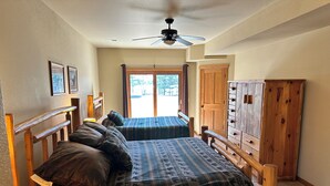 A bedroom with two beds, wooden headboards, a ceiling fan, and a large window with curtains. - Spirit of the Northwoods (eagle river)