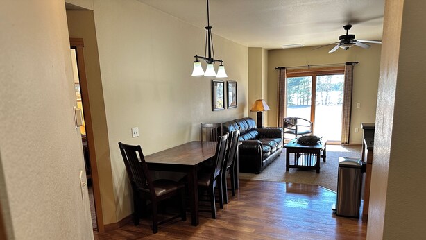 A spacious dining area with a wooden table and chairs, a sofa, and a ceiling fan. - Spirit of the Northwoods (eagle river)