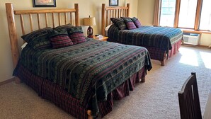 A bedroom with two beds, a ceiling fan, a window with curtains, and a framed picture on the wall. - CONDO 107 by Eagle Waters Resort (eagle river)