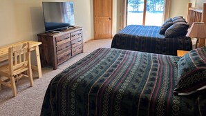 A bedroom with two beds, a wooden dresser, a TV, and a window with curtains. - Spirit of the Northwoods (eagle river)