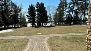 A paved pathway leading through a grassy area with trees in the background. - Spirit of the Northwoods (eagle river)