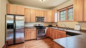 Una cocina con armarios de madera, electrodomésticos de acero inoxidable y un ventanal.
