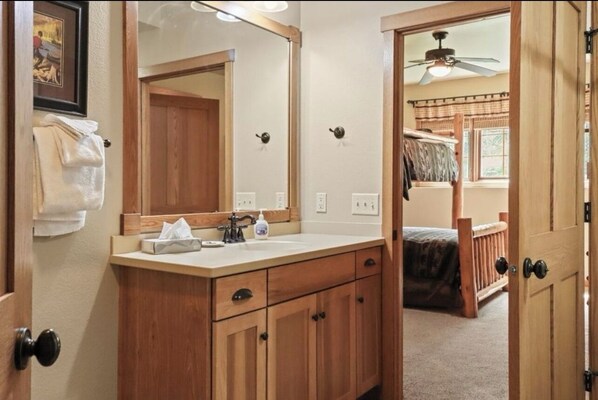 Un baño con muebles de madera, un lavabo y un espejo grande.