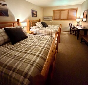 A bedroom with two beds, a desk, and a chair.