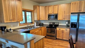 A kitchen with wooden cabinets, stainless steel appliances, and a granite countertop. - CONDO 201 by Eagle Waters Resort (eagle river)