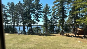 A grassy area with a wooden deck, a small cabin, and a lake in the background. - Spirit of the Northwoods (eagle river)