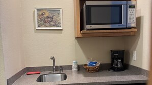 Une cuisine compacte équipée d’un évier, d’un four à micro-ondes, d’une machine à café et d’un lave-vaisselle.