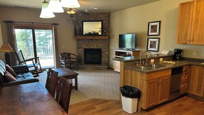 A spacious kitchen with wooden cabinets, a built-in dishwasher, and a stone fireplace. - CONDO 202 by Eagle Waters Resort (eagle river)