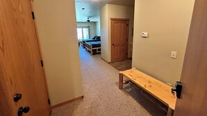 A hallway with a wooden bench, carpeted floors, and a door leading to a bedroom with a bed and a ceiling fan. - Studio 212 By Eagle Waters Resort (eagle river)