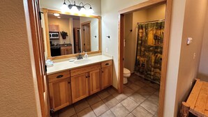 A bathroom with a wooden vanity, a large mirror, and a shower curtain with a nature print. - Studio 212 By Eagle Waters Resort (eagle river)