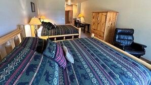 A bedroom with two beds, a ceiling fan, a wooden wardrobe, and a black leather chair. - Studio 212 By Eagle Waters Resort (eagle river)