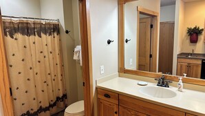 Un baño con tocador de madera, lavamanos, espejo y retrete.