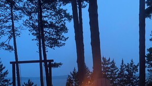 A campfire in a metal fire pit surrounded by rocks, with a wooden bench and a swing set in the background. - Condo 206 W/ Garage by Eagle Waters Resort (eagle river)