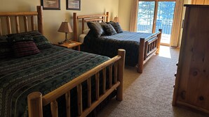 A room with two wooden beds, a ceiling fan, and a view of the outdoors through a large window. - SUITE 206 W/ Garage@EAGLE WATERS RESORT (eagle river)