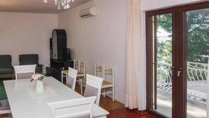 A dining area with a chandelier, a TV, and a view of the outdoors. - Apartment in Sibenik by Sandy Beaches (Sibenik)