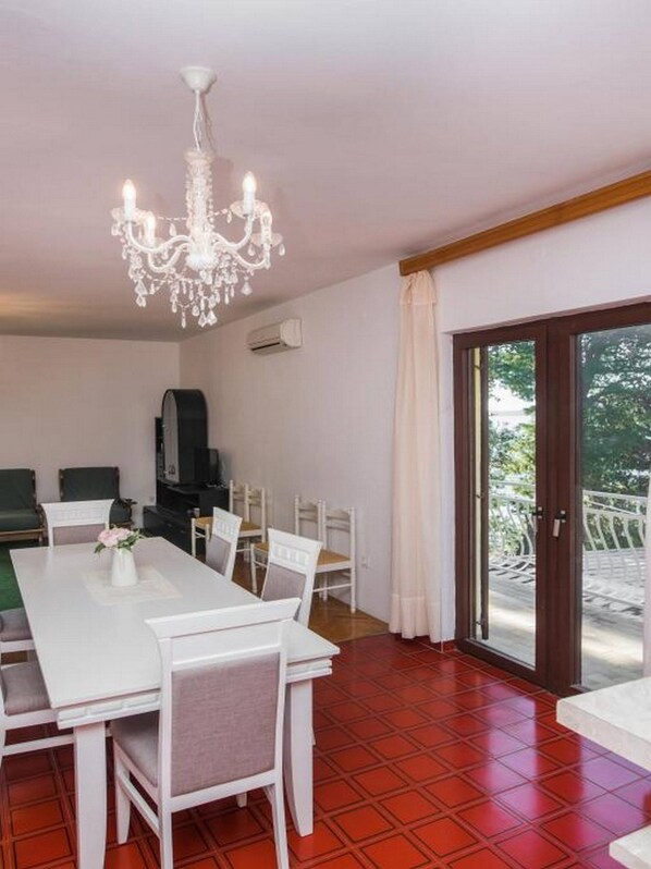 A dining area with a chandelier, a TV, and a view of the outdoors.