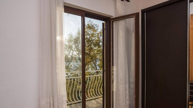 A room with a sliding glass door leading to a balcony with a metal railing. - Apartment in Sibenik by Sandy Beaches (Sibenik)