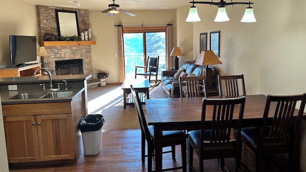 A spacious living area with a fireplace, a dining table, and a kitchen with a stone accent wall.