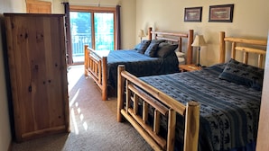 A bedroom with two wooden beds, a ceiling fan, and a view of the outdoors.