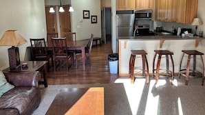 A spacious kitchen with wooden cabinets, a stainless steel refrigerator, and a bar area with stools.