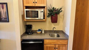 Cocina compacta con microondas, cafetera y lavamanos.