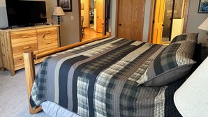 A bedroom with a large bed, wooden dresser, and a television. - CONDO 301 by Eagle Waters Resort (eagle river)