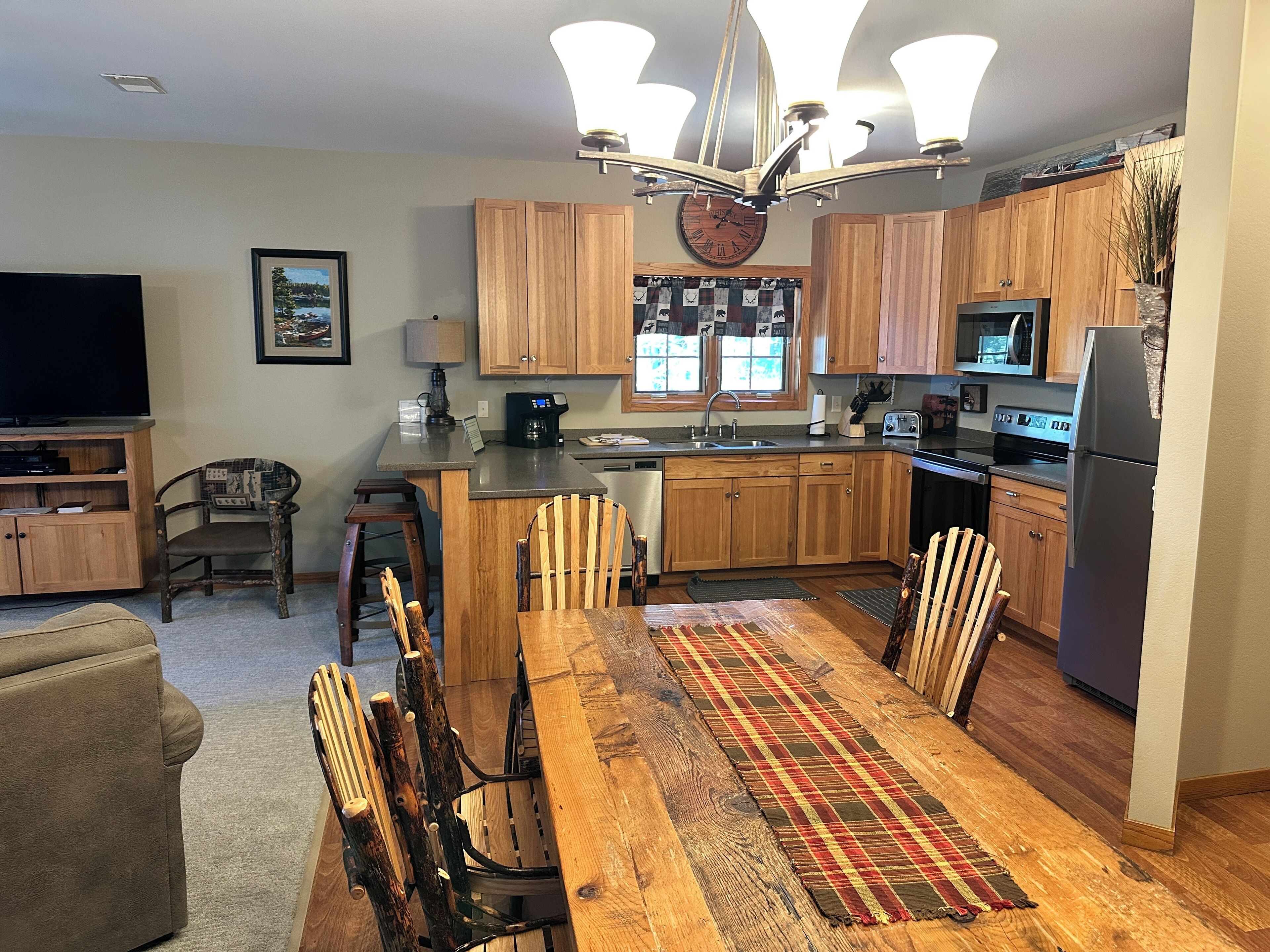 A modern kitchen with wooden cabinets, a central island, and a dining area with a wooden table and chairs.