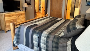 A bedroom with a large bed, wooden dresser, and a television. - Spirit of the Northwoods (eagle river)