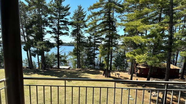 A fenced outdoor area with a view of a lake and trees. - Spirit of the Northwoods (eagle river)