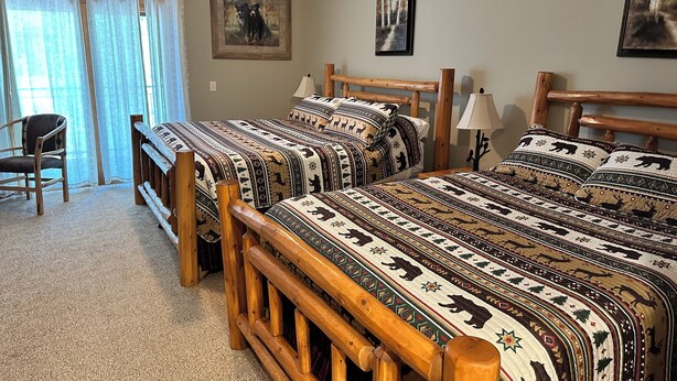 A room with two wooden beds, a chair, and a ceiling fan. - Studio 311 by Eagle Waters Resort (Eagle river)