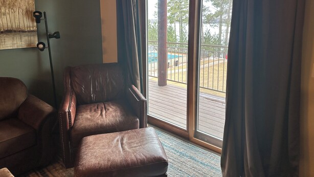 Ein Zimmer mit Ledersessel, großem Fenster mit Vorhängen, einem Gemälde an der Wand und einem Schild über dem Fenster mit der Aufschrift 'Wild'.